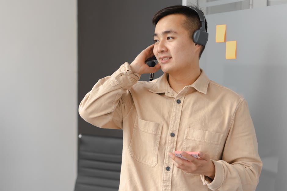 Asian man in office wearing a headset engaged in