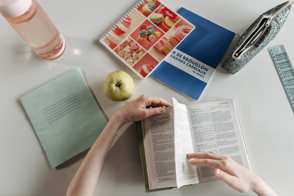 Overhead view of hands turning book pages at a stu