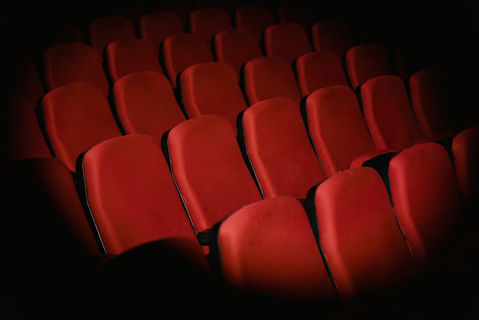 Rows of empty red armchairs in a dimly lit cinema